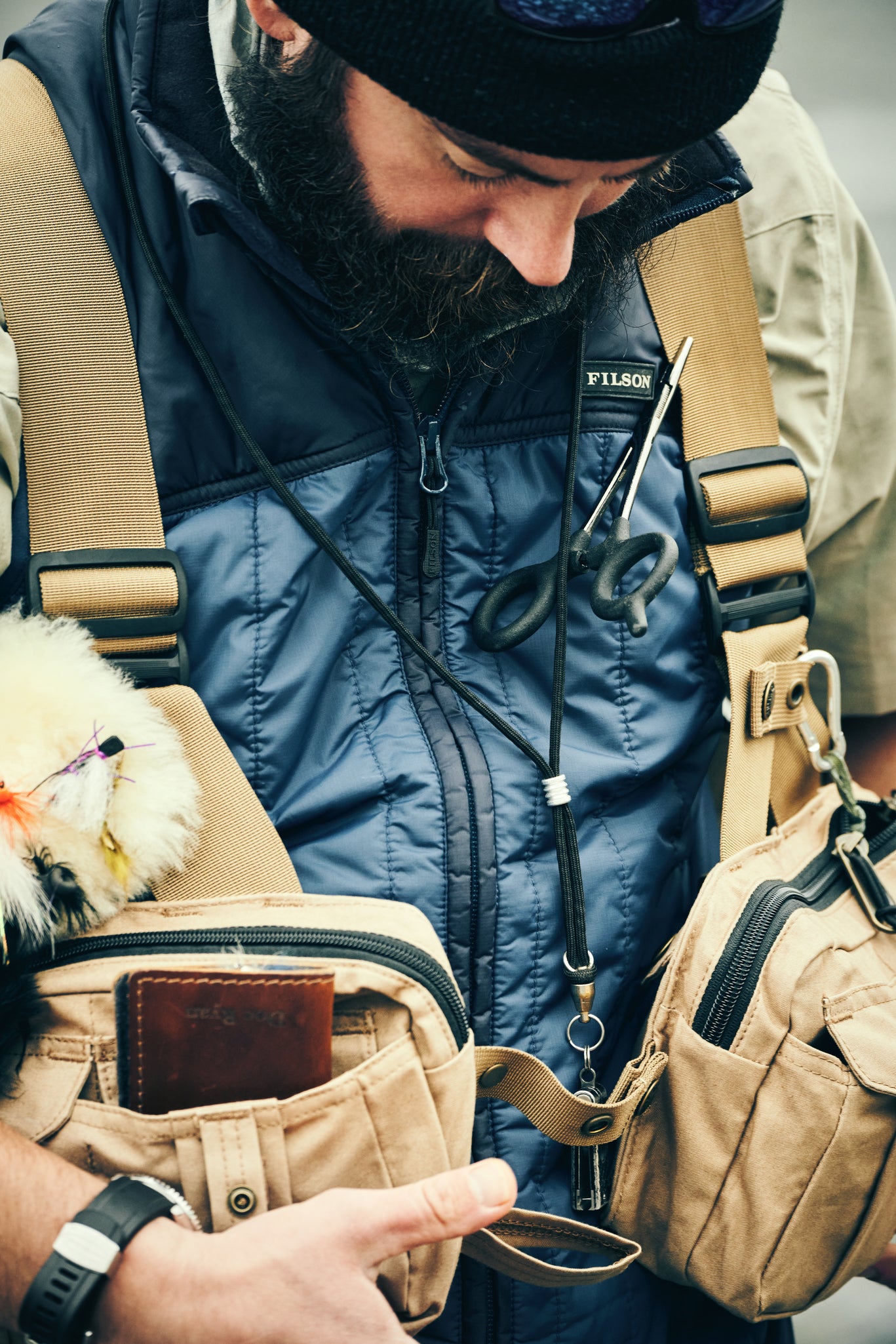 Man wearing Filson Mesh Fishing Strap Vest in dark tan looking downwards