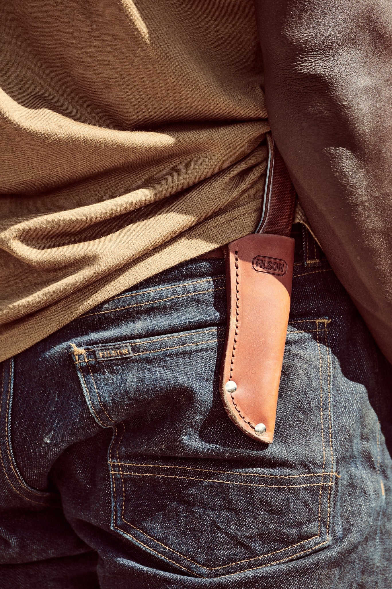 Man wearing denim with a Filson Bird & Trout knife in a sheath on his belt